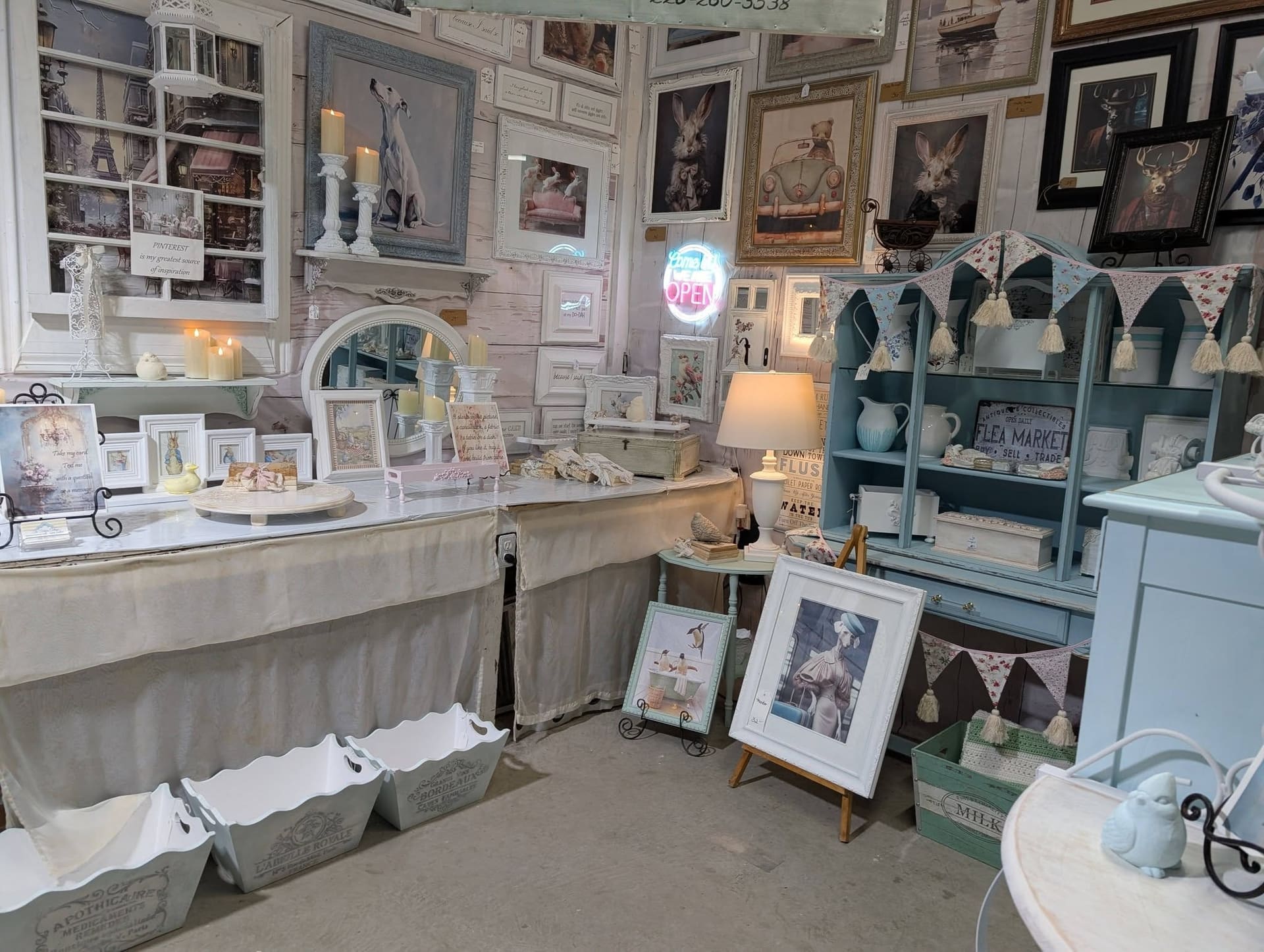 A consignor booth of white-painted furniture and framed prints